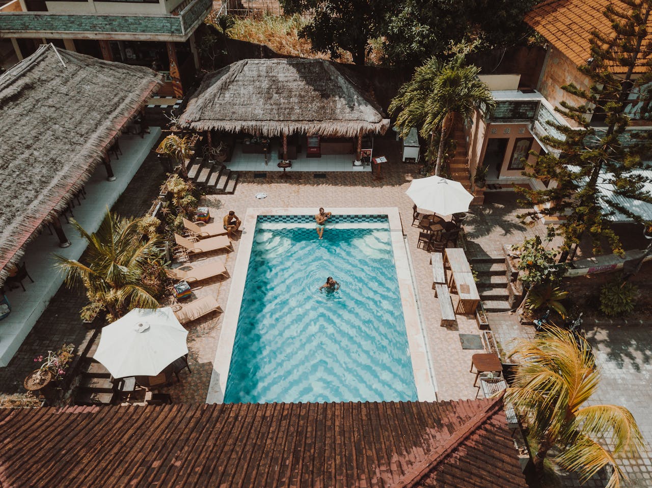 Aerial view of a luxury resort pool surrounded by villas and palm trees.