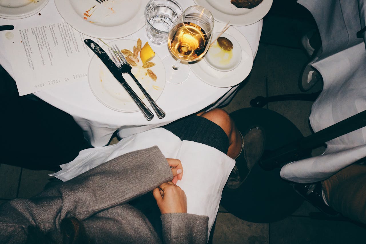 A top-down view of a dining table with elegant table setting and a glass of white wine.